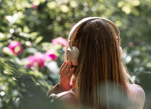A woman walking amongst flowers listening to music in her headphones