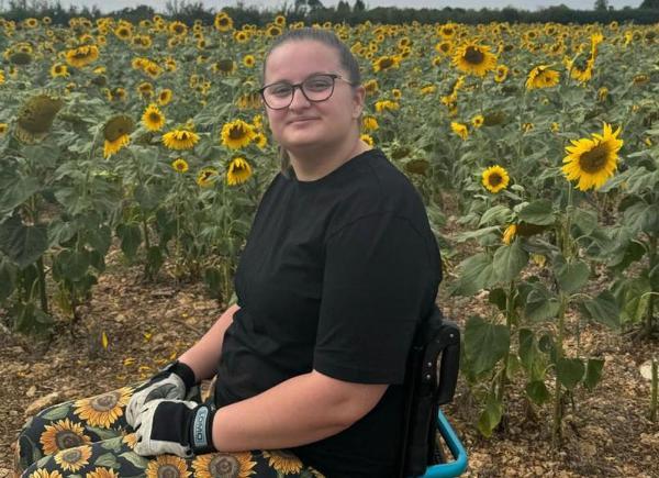 A young woman in a wheelchair sitting in a field of sunflowers