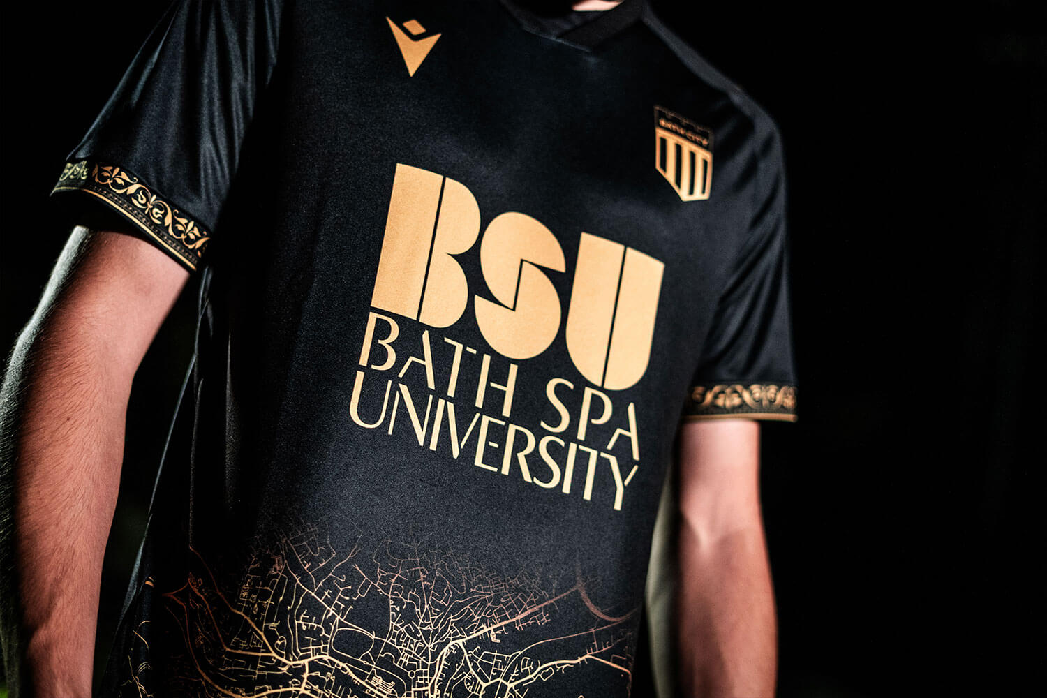 A black and gold football shirt with the Bath City FC logo and Bath Spa University logo emblazoned on the front