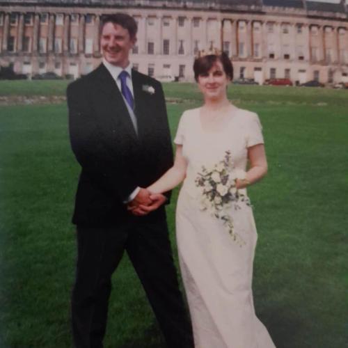 A couple hold hands and pose for a photo on their wedding day