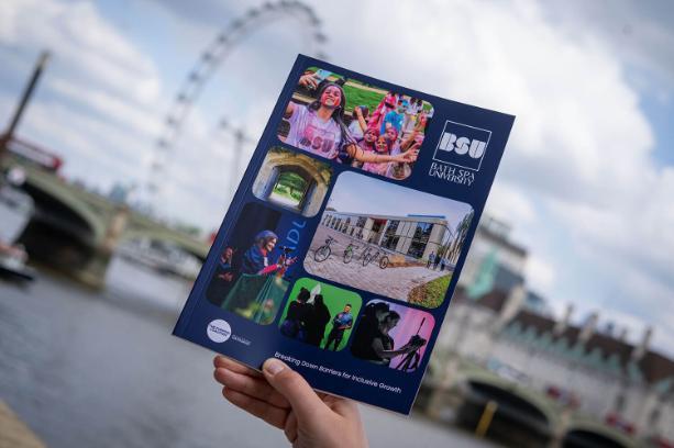 Someone holds up a BSU booklet against a view of London