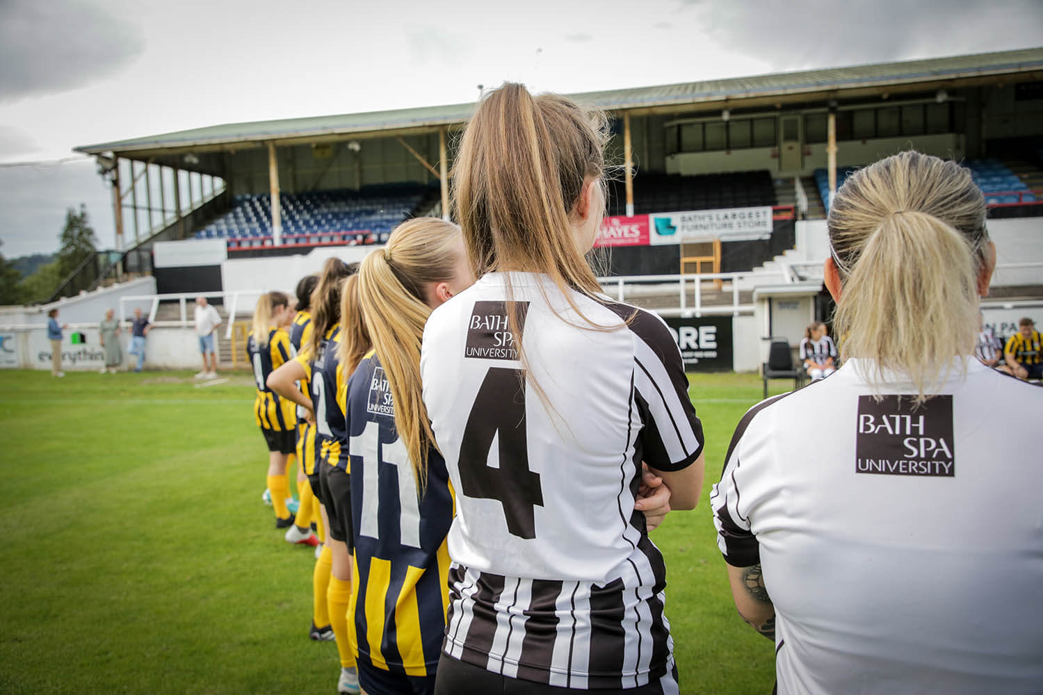 A footballer wearing her shirt with the Bath Spa logo on the back