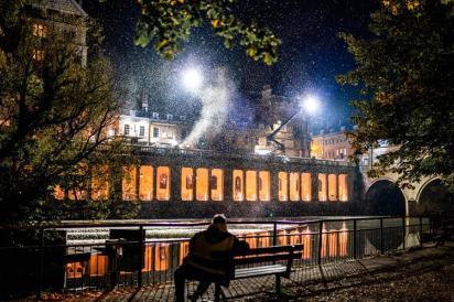 A dark river is illuminated by lights and falling snow