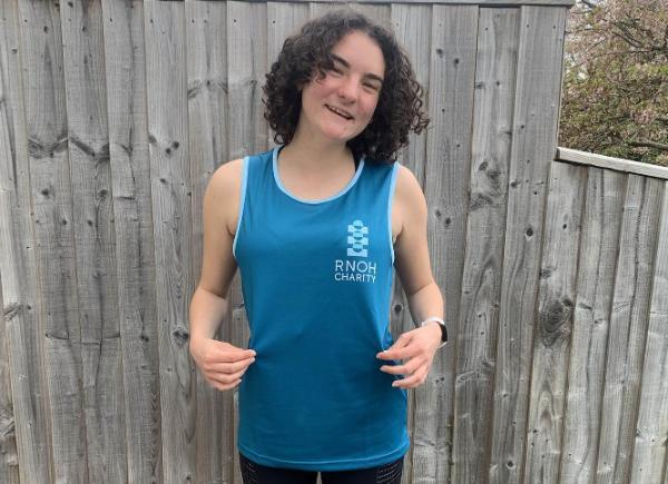 Becky Farrell smiling in a blue running top with RNOH logo on it.