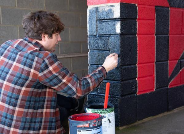 BSU Lecturer Jonathan Kelham painting a wall black at Brislington FC