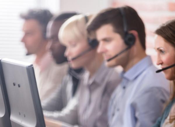 people sat at a long table wearing headsets and looking at computer screen