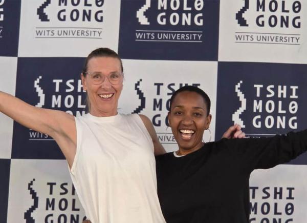 Two women with their arms around one another pose for a photo