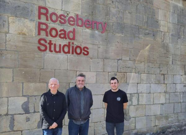 Three men stand outside the front of a building with a sign reading 'Roseberry Road Studios'