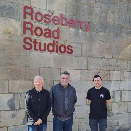 Three men stand outside the front of a building with a sign reading 'Roseberry Road Studios'