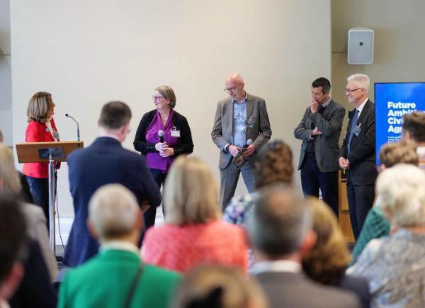 A room full of people listen to a talk