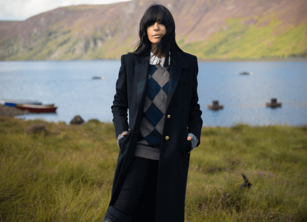 Claudia Winkleman stands in the countryside, looking at the camera.