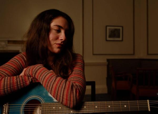 A girl sat in a chair holding a guitar