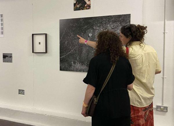 Two women pointing at an exhibition of artwork