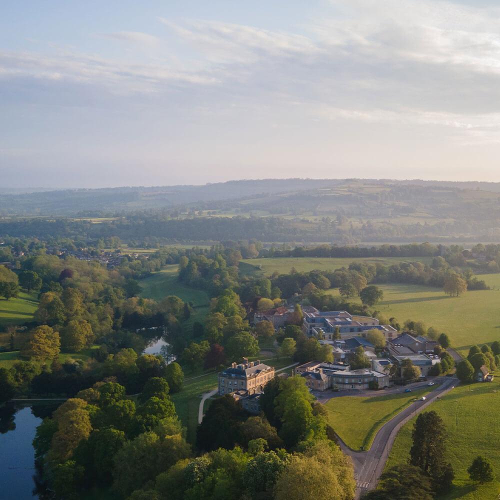 a drone shot of the BSU campus, showing rolling fields and buildings cast in the setting sun