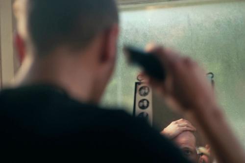 Color photo of Finlay Mills shot from behind with his reflection in a mirror