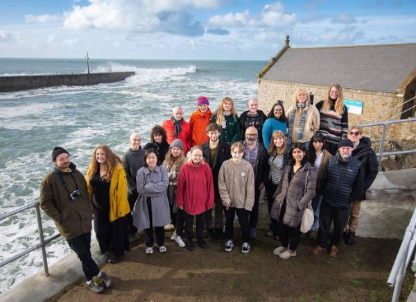 A group of people posing by the harbour in Porthleven.