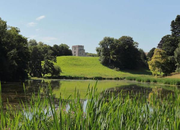 Newton Park lake with blue skies and the castle at the top of the hill