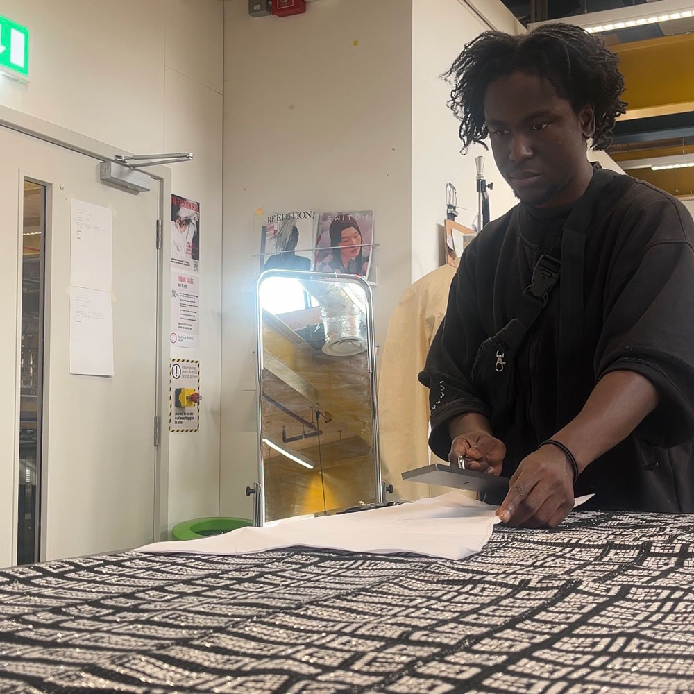 Hansel cutting into some patterned fabric in his workspace at Locksbrook Campus
