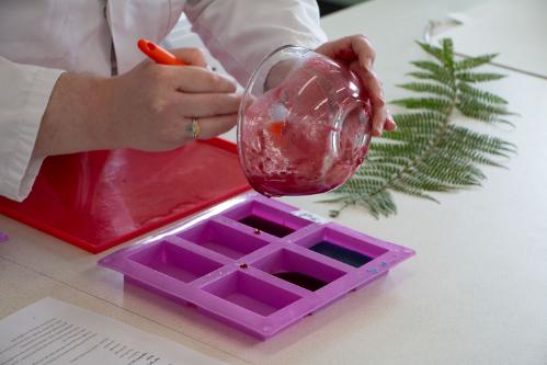 A person pouring melted material into some molds