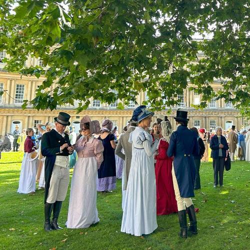 a group of people standing outside the Circus in Bath, wearing regency clothing