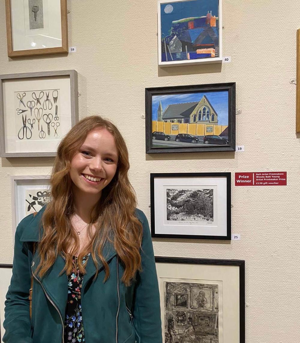 Award-winning Bath Spa artist Jenna Axell standing in front of some of her art