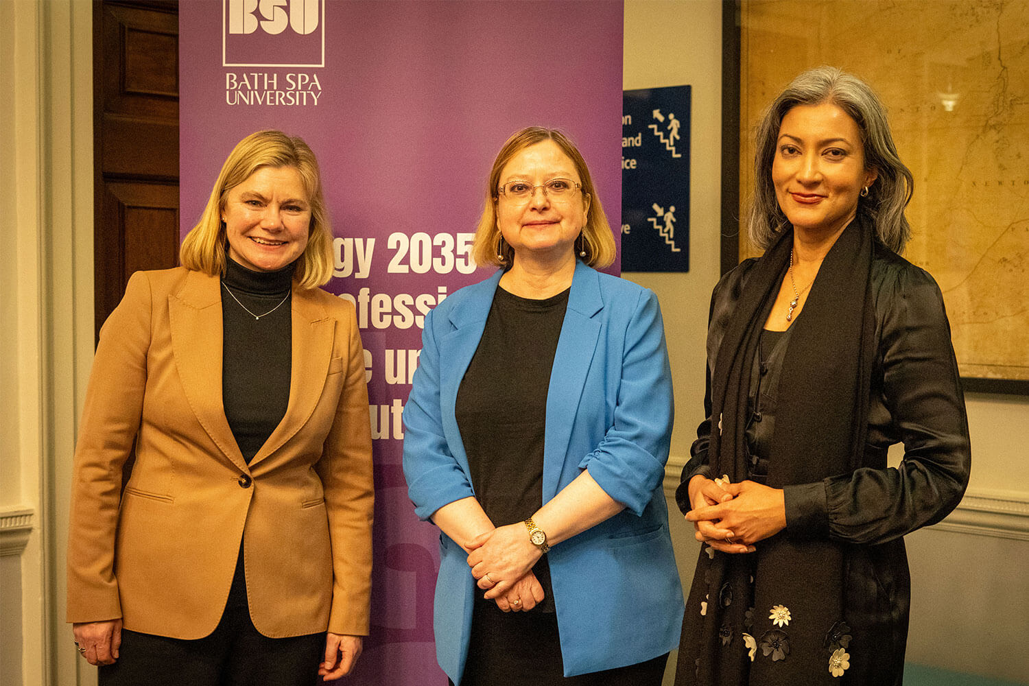 three people smartly dressed stood in front of a BSU branded banner announcing new strategy