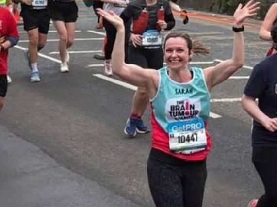 A marathon runner with her hands raised in the air while running