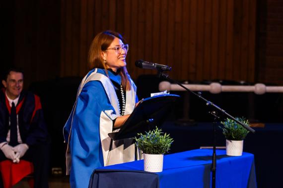 A woman gives a speech while wearing blue robes