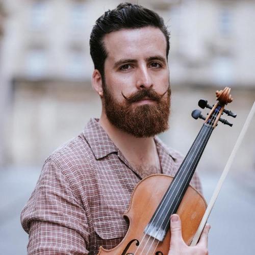 Nik Jovcic-Sas poses with his violin. They have a beard and a stylish moustache with upturned corners.
