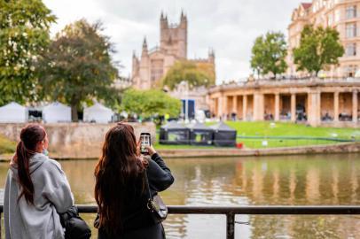 A girl takes a photo of a river and a film set