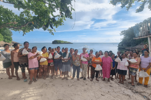 A group of people pose together on a beach in the Philippines