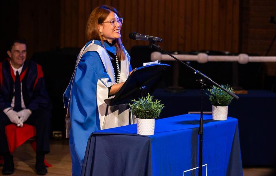 Ping Coombes gives a speech in a blue robe