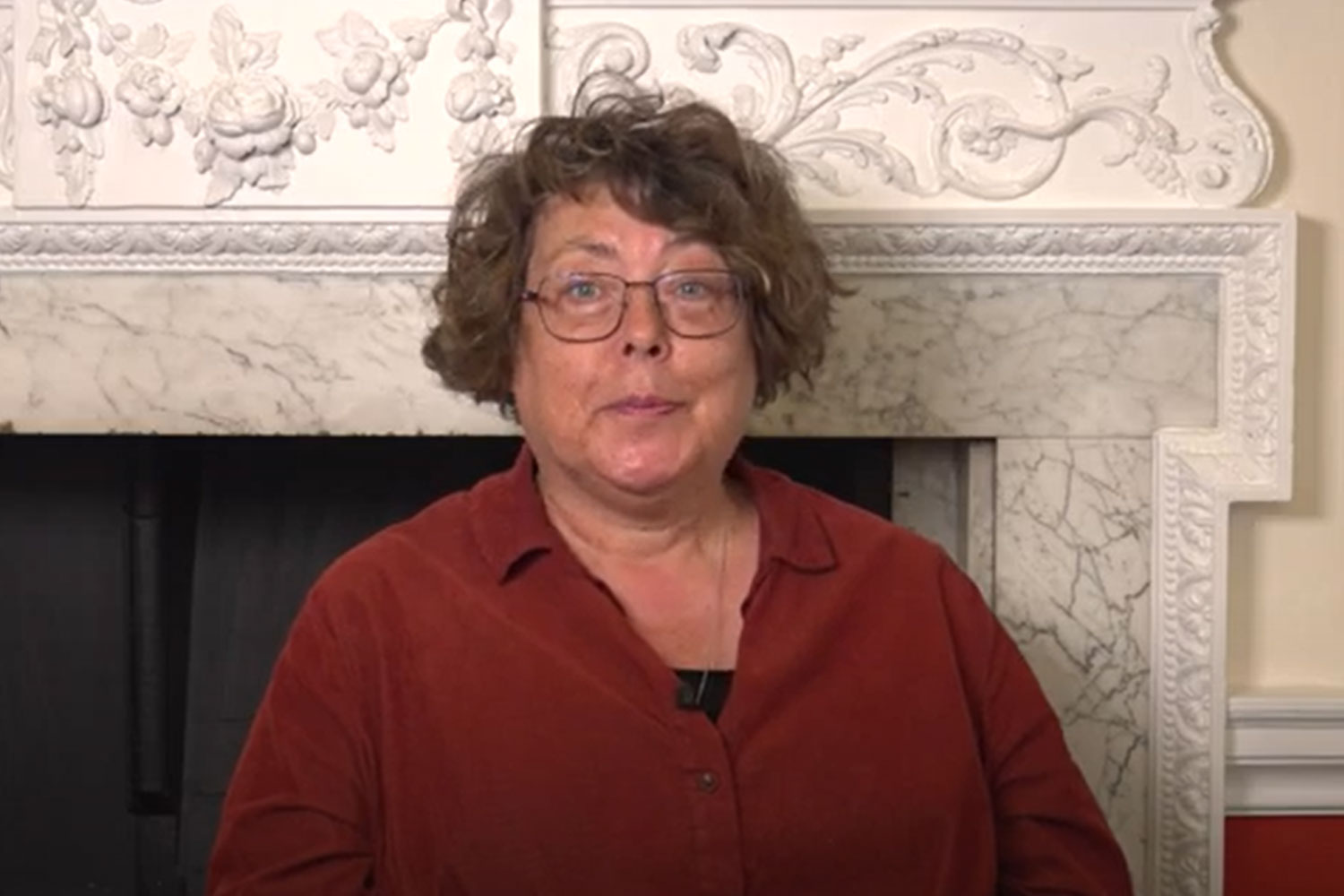Headshot of Professor Rigby in front of ornate fireplace
