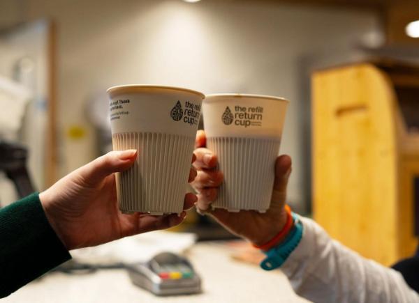 Two reusable cups being held in the air to cheers