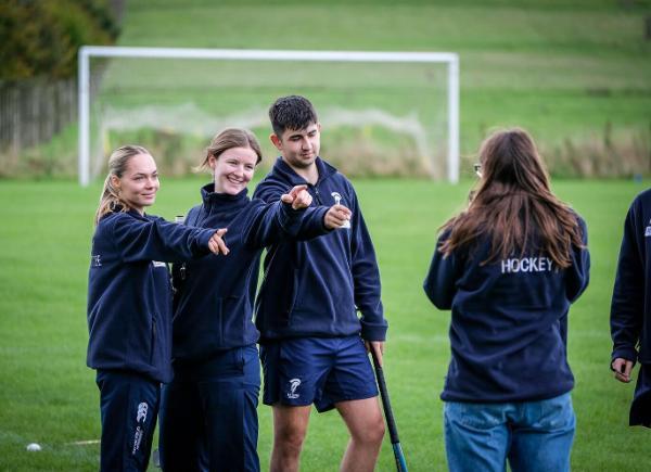 people in hockey jackets on sports pitch