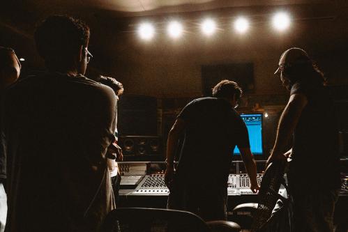 A group of people gathered in a studio. They are backlit and one is about to press a button.