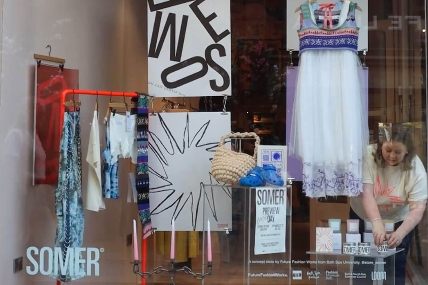 The front of a clothing store, with posters and clothes in the window