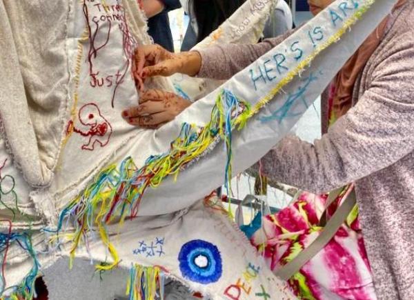 A person embroidering on a sculpture made of fabric