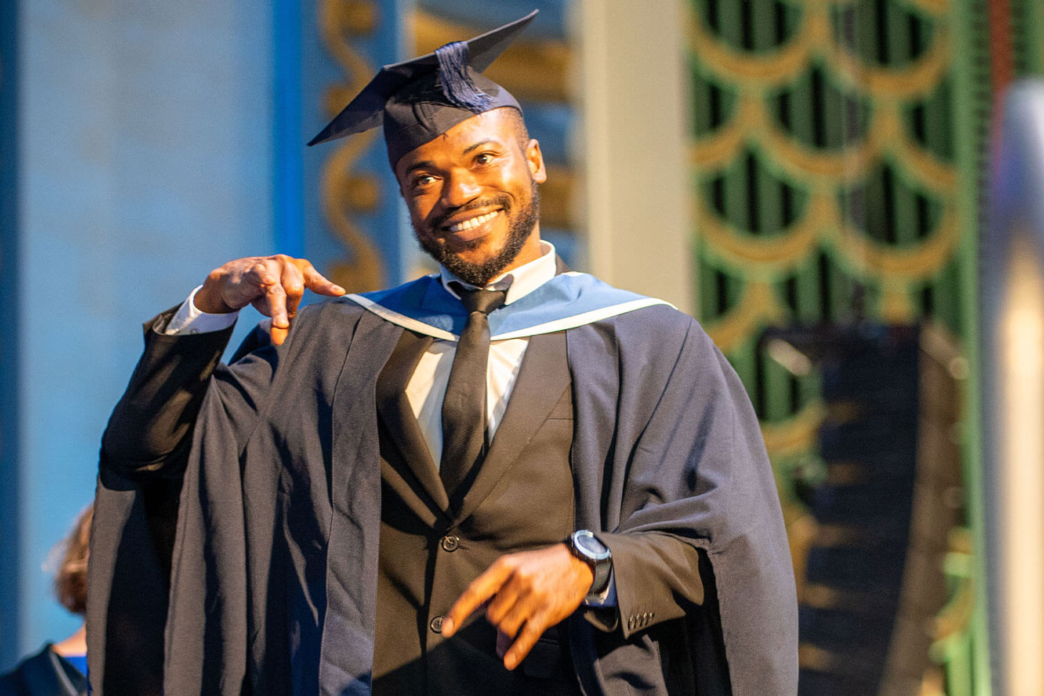 A student posing for the camera in graduation robes