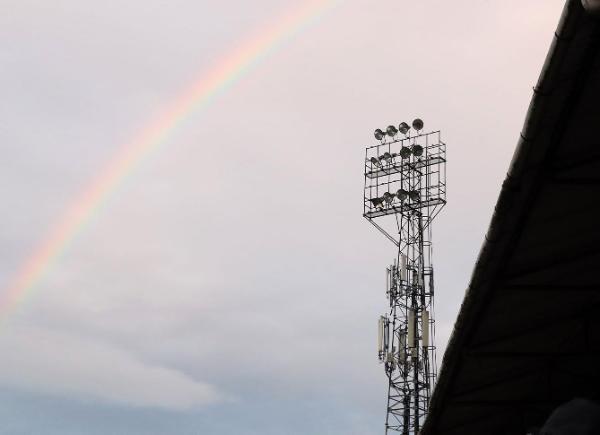 A football ground floodlight in front of a rainbow