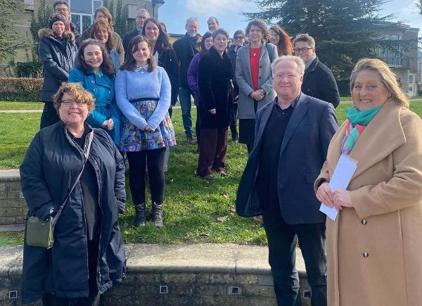 A group of people gathered outdoors on a sunny day, standing next to two commemorative plaques
