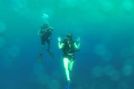 Two people are scuba diving and posing for a photo underwater