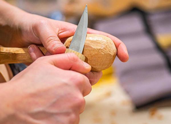 A pair of hands whittling a piece of wood with a knife