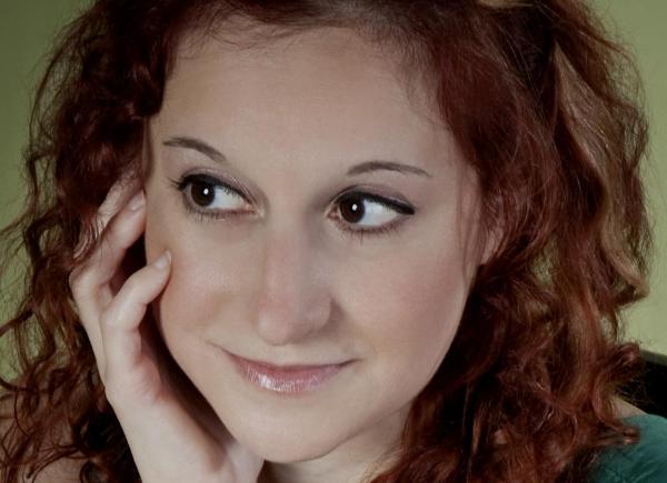 Headshot of a woman with reddish hair looking thoughtfully into the distance