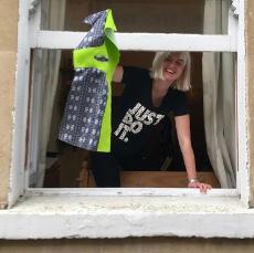 Design student holding up garment hanging it out of a window