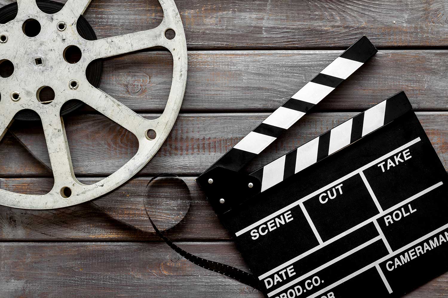A film reel and clapperboard lying on a wooden table