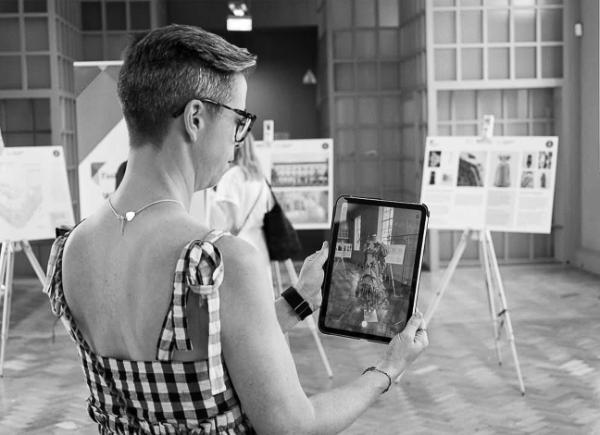 A black and white photo of a woman digitally scanning a piece of clothing