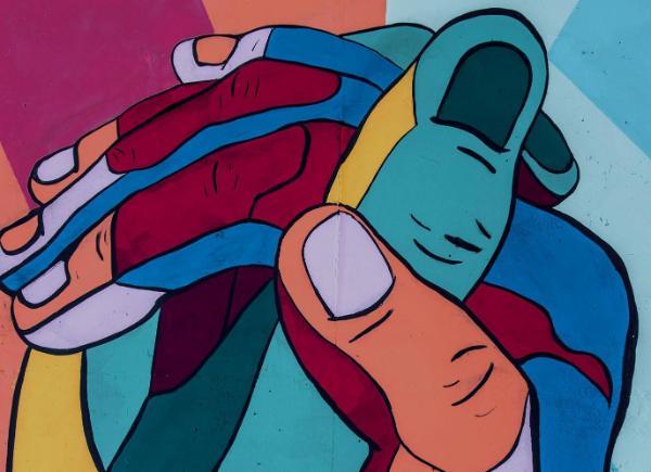 Painted image of hands clasped in bright multicolours