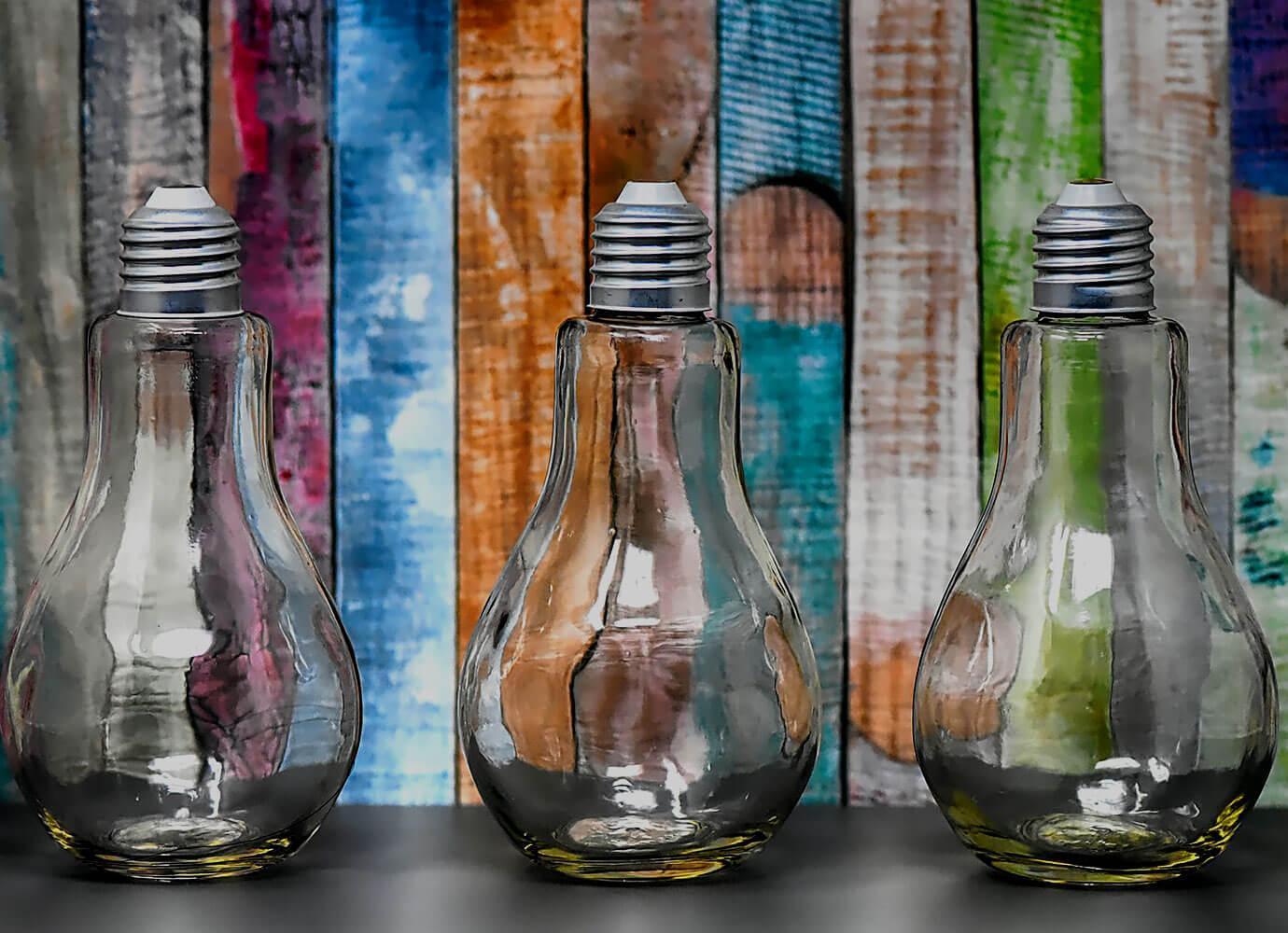 Three glass lightbulbs against a colourful background