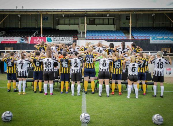 Bath City Women FC point to the back of their shirts